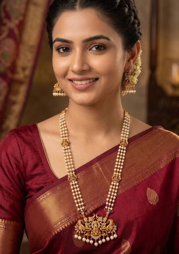 South indian Women wearing a Jadau Kundan Gold Plated Temple Lakshmi Devi Beaded Necklace with Earrings design with pearl drop hangings with three row chain with whitw pearl drops . perfect for weddings