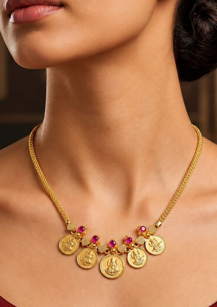 A close-up of a model wearing a Exquisite Goddess Laxmi gold-plated coin necklace featuring intricate motif carvings and ruby-colored stone accents. Ideal for weddings, festive occasions, temple visits, traditional sarees, and bridal gifting.