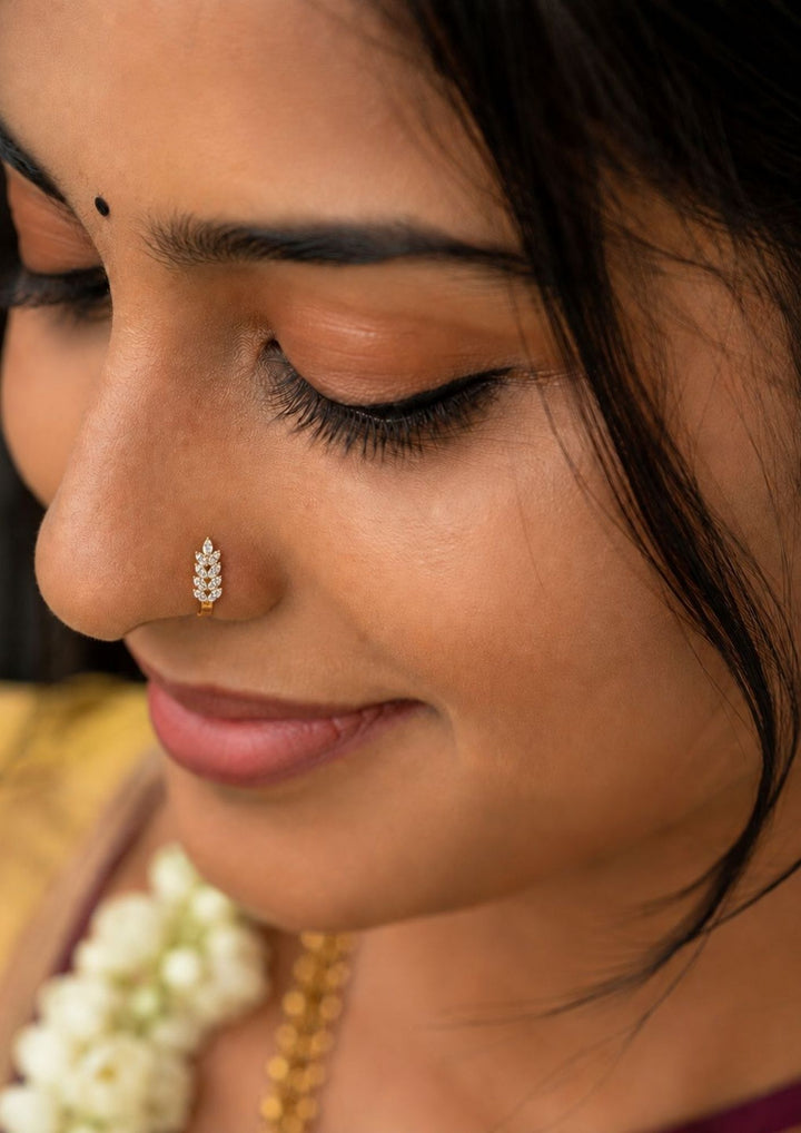 Close-up of a south indian woman wearing Gold-plated nose pin design with leaf design using zircon diamonds with back open its perfect for weddings, dailywear and it is antifade color.