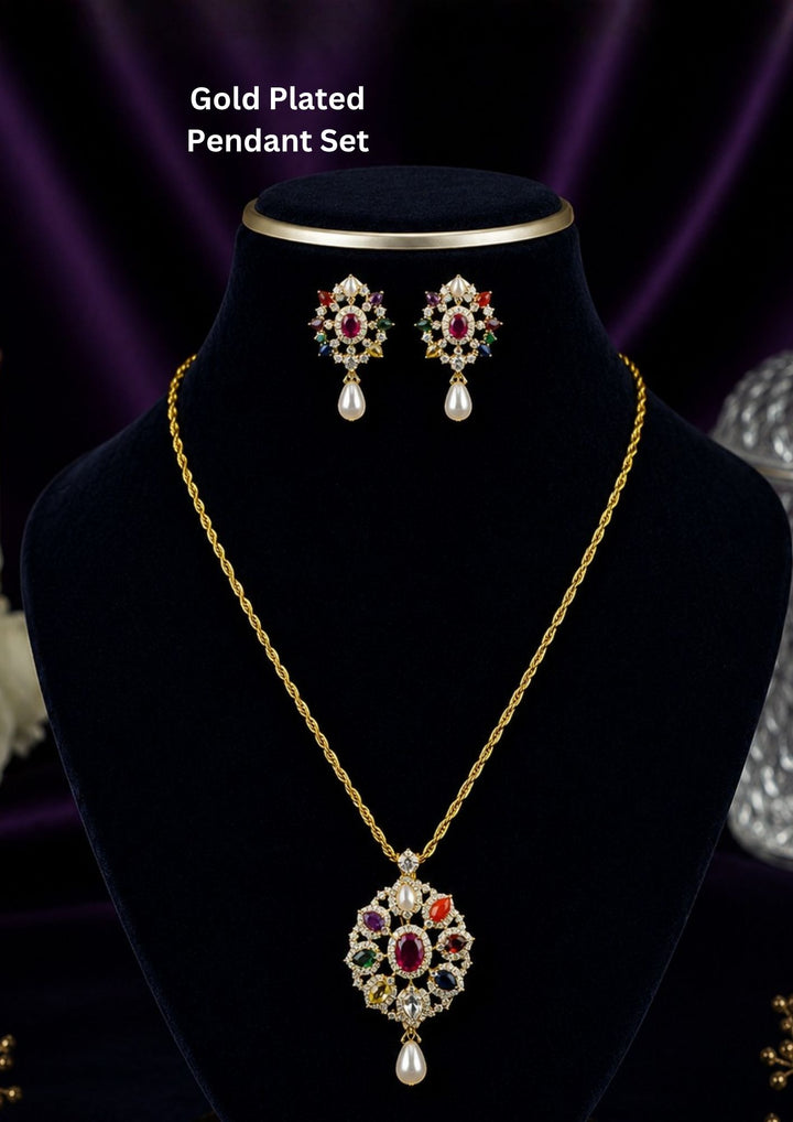 Gold-plated pendant necklace and matching stud earrings displayed on a black velvet jewelry bust. The necklace features a detailed floral pendant with red, green, and blue stones, while the matching earrings are shown above the bust.