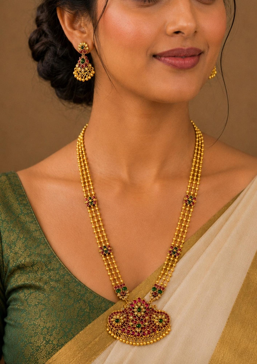 South Indian Woman wearing a Gold-plated necklace set with intricate design long necklace Setand earrings  with green and red stones come with jadau kundan in necklace set  with beads and in pendent and earrings shows clear design and in detailed shown in picture it will not fade color and water proof can used for festivals, bridals, and weeding&