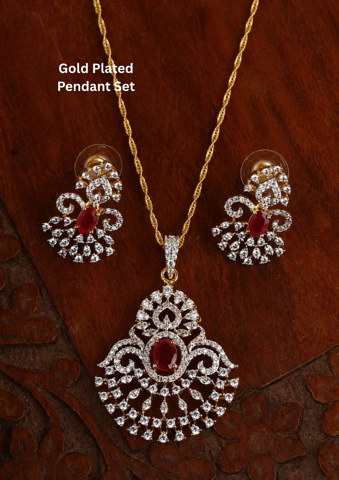 Zircon diamond gold plated pendant and earring set featuring a large open teardrop style chandelier pendant filled with tiers of shimmering white zircons and an oval-cut central ruby red gemstone. This lightweight matching set comes with smaller identical teardrop ruby earrings, providing an exceptionally brilliant diamond-look appearance suitable for weddings, receptions, festivals, cocktail parties, sarees, gowns, and ethnic fusion wear with skin-friendly quality, anti-fade premium polish, comfortable 