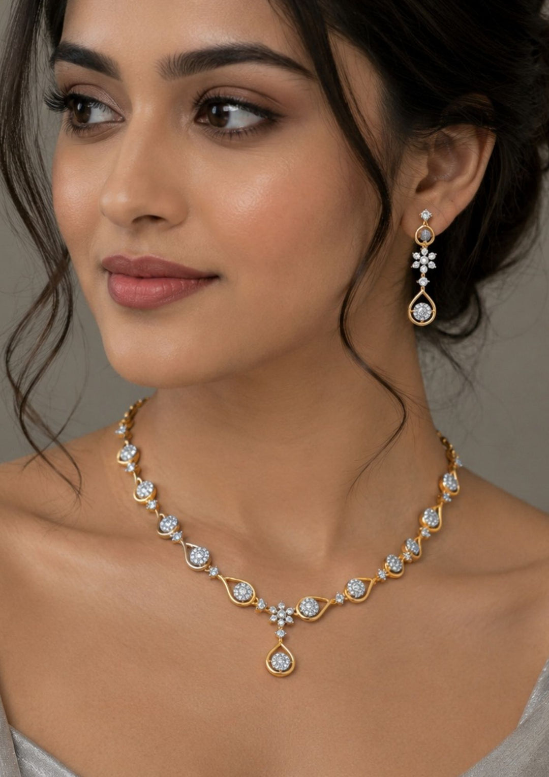 South Indian Woman wearing A sleek zircon diamond gold plated necklace set  features a delicate, undulating gold wave chain studded with round-cut sparkling white stones, transitioning into a central floral accent and a hanging open-teardrop solitaire pendant with matching dangling earrings.
