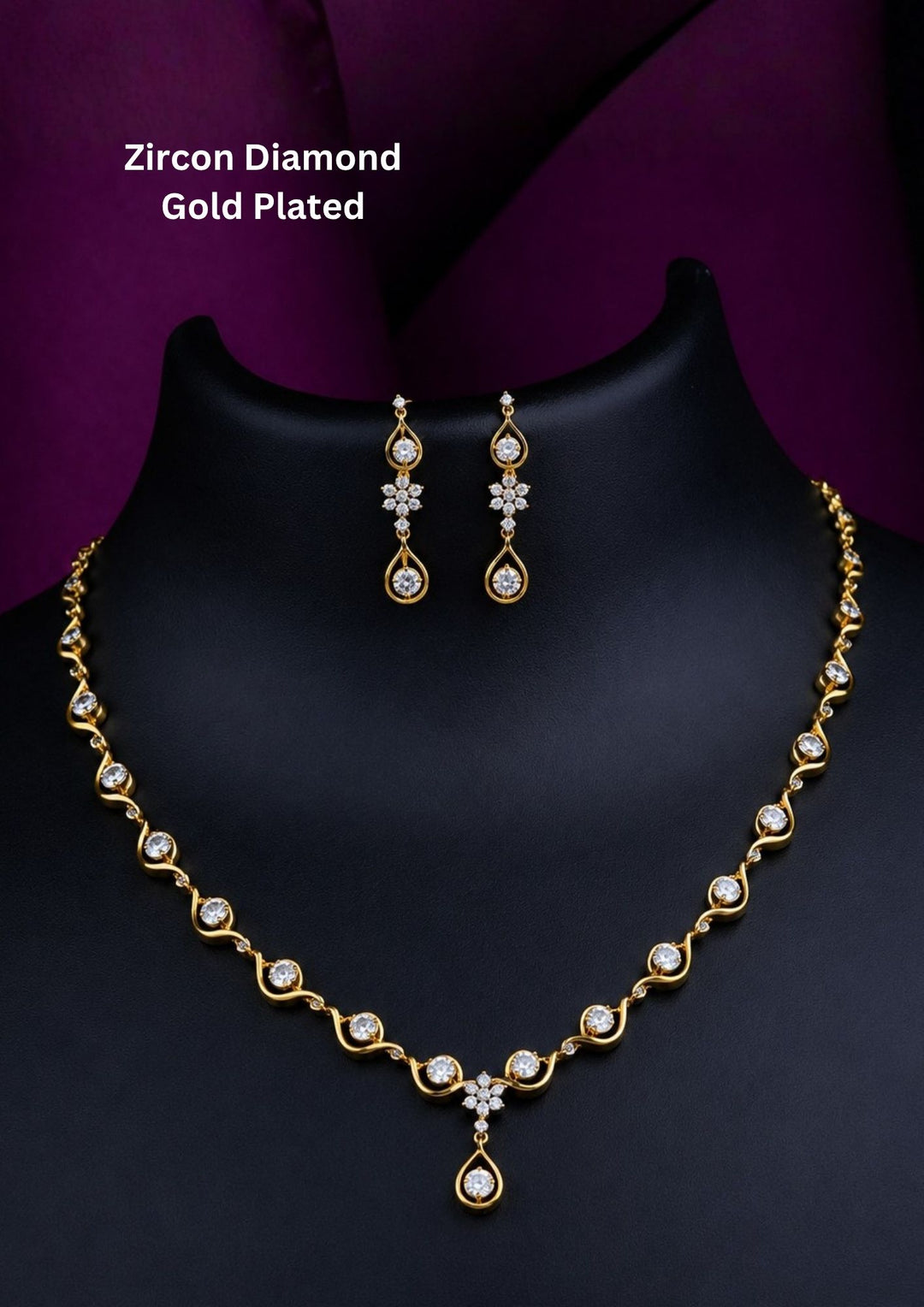 A sleek zircon diamond gold plated necklace set  features a delicate, undulating gold wave chain studded with round-cut sparkling white stones, transitioning into a central floral accent and a hanging open-teardrop solitaire pendant with matching dangling earrings.