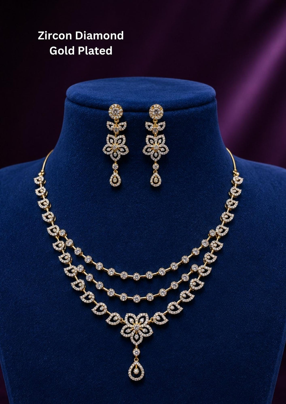 Elegant zircon diamond gold plated jewelry set featuring a triple-layered necklace and matching drop earrings. The set showcases intricate floral and leaf-inspired motifs studded with sparkling white zircon stones, ending in a delicate teardrop dangle against a deep blue display bust.