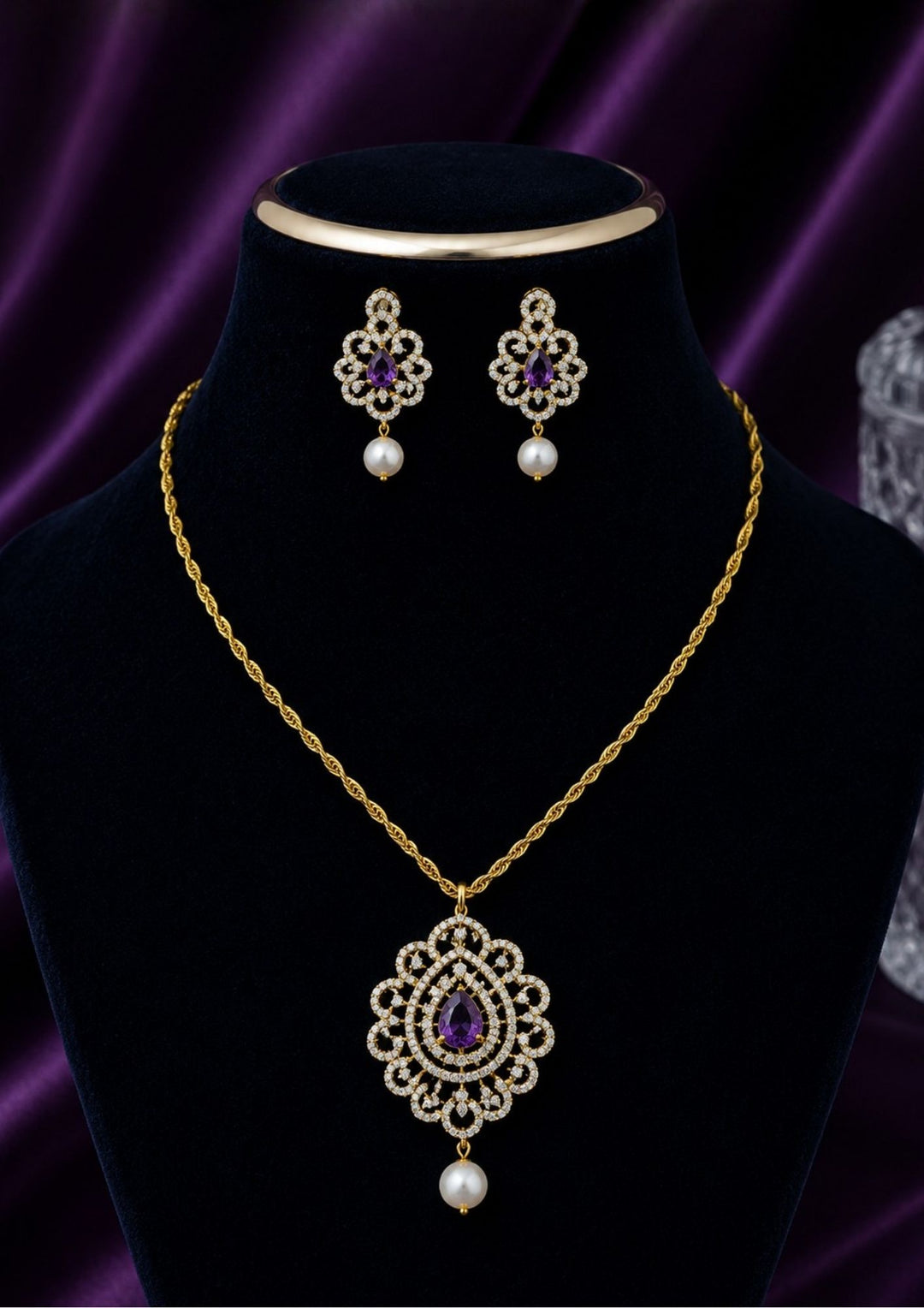 Elegant zircon diamond gold plated pendant set featuring a floral-inspired pendant designed with sparkling white zircon stones arranged in circular patterns. The centerpiece showcases a pear-shaped emerald violet stone surrounded by dazzling zircon stones, finished with a delicate pearl drop. The matching earrings mirror the same floral design with green stone and pearl danglers, Perfect for weddings, festivals, office wear, functions and its anti fade color