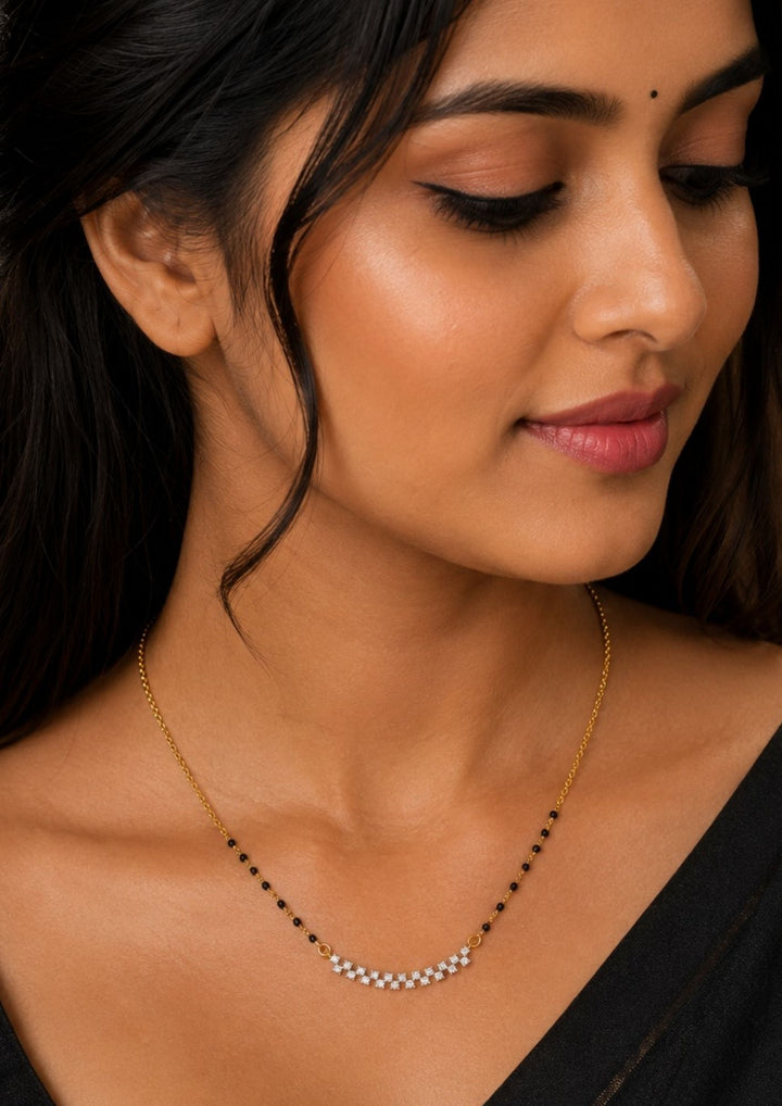 Close-up of a woman wearing a Modern Zircon Diamond gold plated mangalsutra necklace The design features a delicate gold long chain transitioning into sections of traditional small black beads on both sides. The central pendant showcases a sleek, contemporary curved Zigzag pendant with sparkling white cubic zirconia stones. This elegant neckpiece perfect for daily wear, office wear, and casual outfits.
