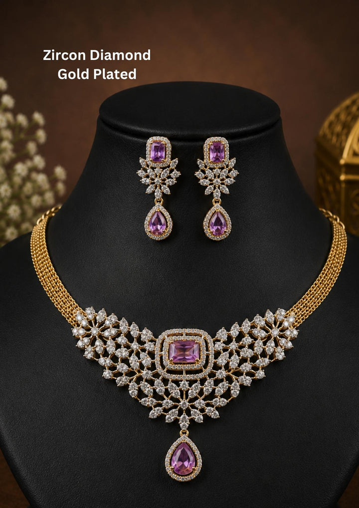 Elegant gold plated necklace set featuring sparkling white zircon stones arranged in a floral lattice pattern with striking purple center stones. The necklace is finished with a pear-shaped purple drop pendant and matching statement earrings, creating a luxurious look for weddings, receptions and special occasions.