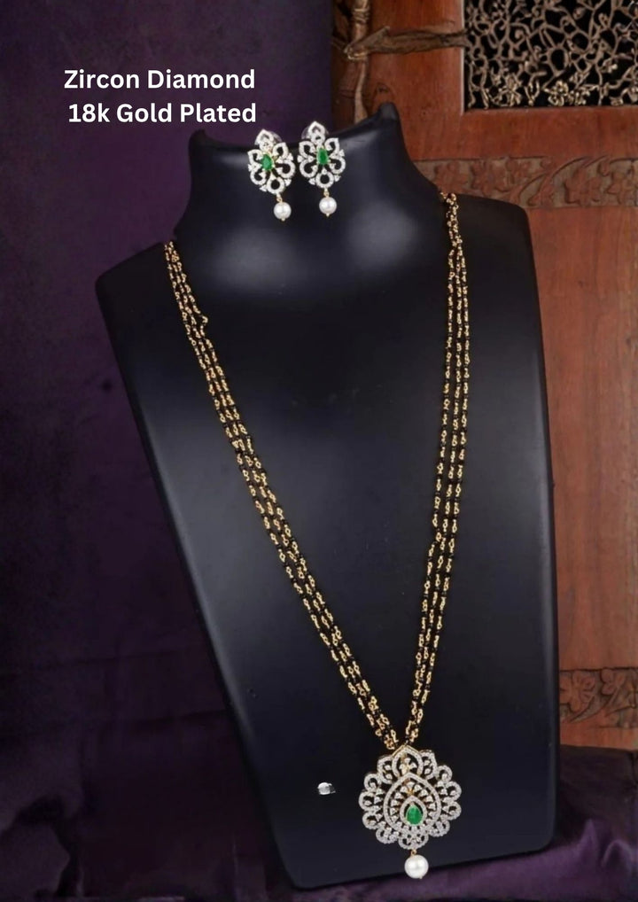 Elegant diamond replica black beads mangalsutra chain featuring a slim gold plated chain with evenly spaced traditional black beads and a curved center pendant decorated with tiny dangling zircon purple stone pendant. The lightweight 24 inch necklace gives a modern minimal look suitable for daily wear, office wear, married women, festive occasions and traditional outfits.