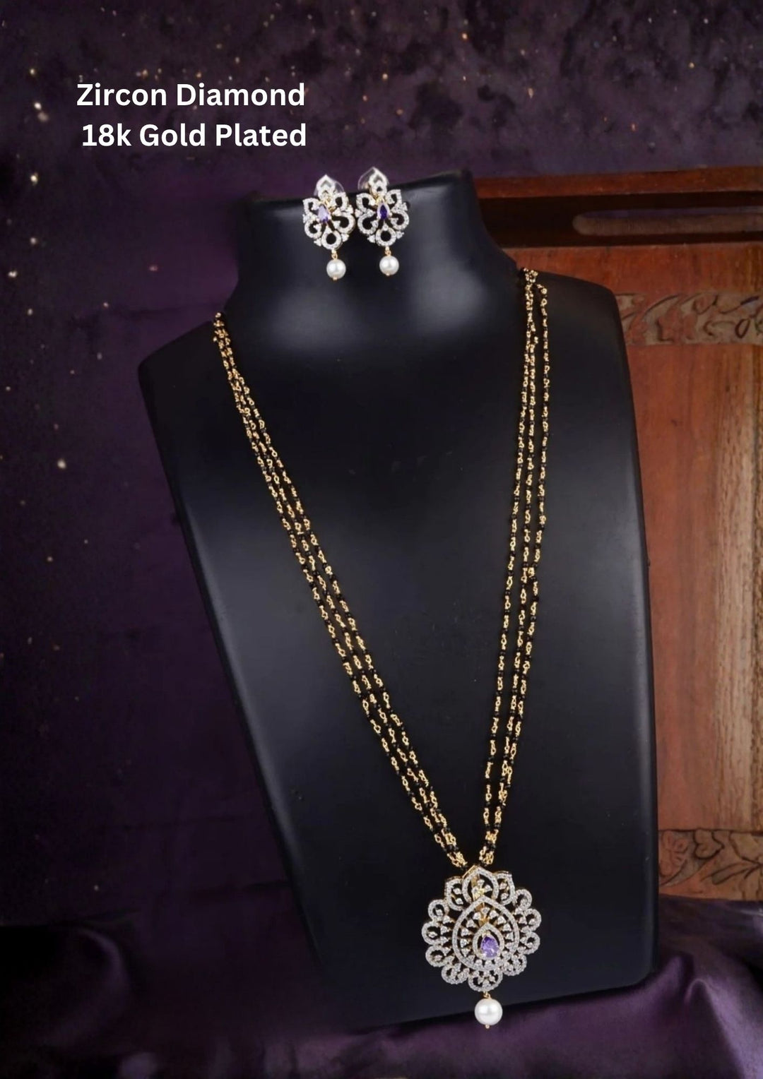 Elegant diamond replica black beads mangalsutra chain featuring a slim gold plated chain with evenly spaced traditional black beads and a curved center pendant decorated with tiny dangling zircon purple stone pendant. The lightweight 24 inch necklace gives a modern minimal look suitable for daily wear, office wear, married women, festive occasions and traditional outfits.